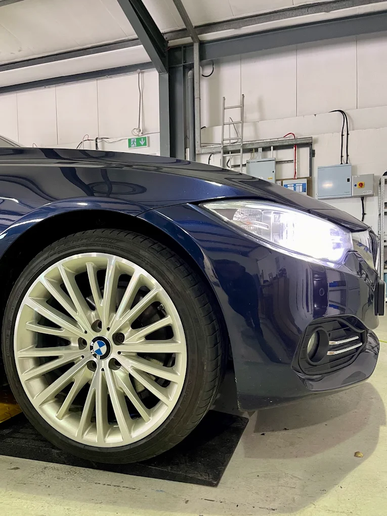 Gloss black alloy wheel powder coating on a stand in the spray booth